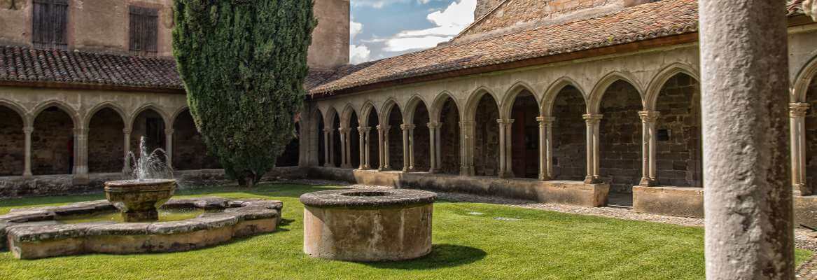 Saint-Hilaire abbey cloister, with arcades and a fountain in the garden